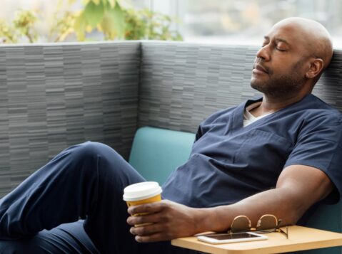 a man sitting on a bench with a cup of coffee