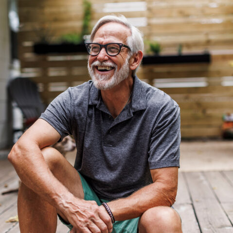 a man sitting on a wooden deck smiling