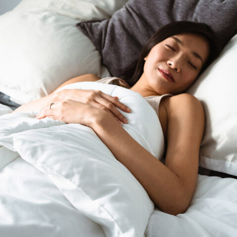 a woman sleeping in a bed with white sheets