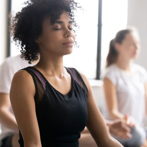 a woman sitting in a yoga position with her eyes closed