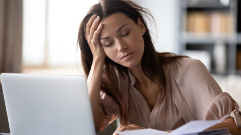 a woman with chronic pain sitting at desk with laptop