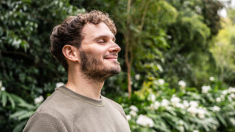 a man standing in front of a lush green forest