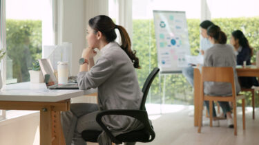 employee loneliness - a woman sitting at a desk in front of a window