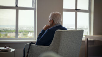 a man sitting in a chair looking out a window