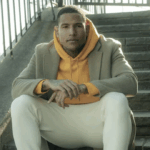 a man sitting on a set of stairs wearing a yellow hoodie