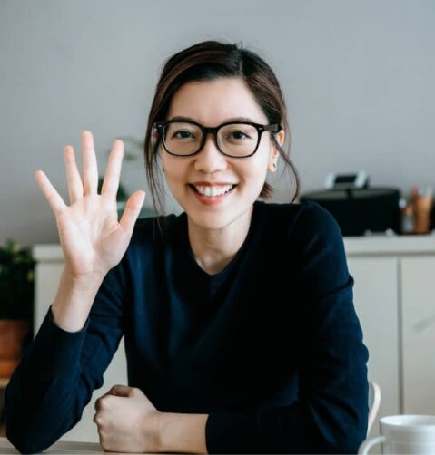 a woman sitting at a table with her hand up in the air
