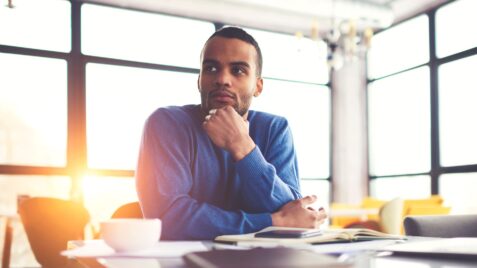 a man sitting at a table in front of a laptop computer