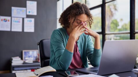 a woman sitting at a desk in front of a laptop computer