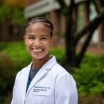a woman in a lab coat standing in front of a building