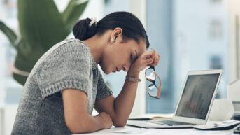 a woman sitting at a desk with her head in her hands