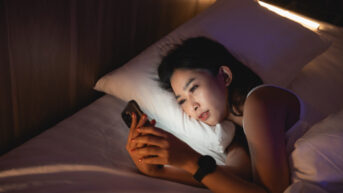 a woman laying in bed looking at a cell phone