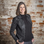 a woman standing in front of a brick wall