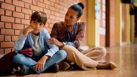 a woman sitting next to a boy on the floor